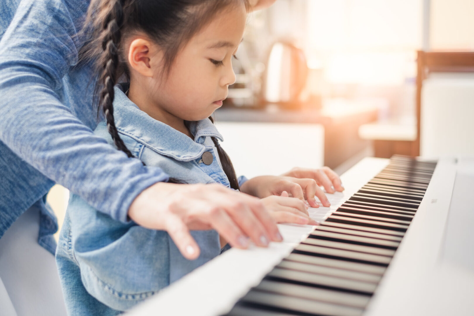 Child receiving piano lesson from adult.